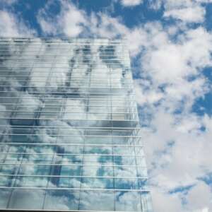 Glass business building with bright blue sky and clouds